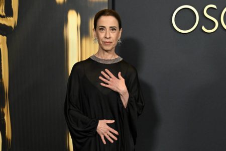 Imagem colorida de mulher usando vestido preto, com o cabelo preso e usando acessórios - Metrópoles