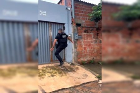 Imagem colorida de policial chutando portão