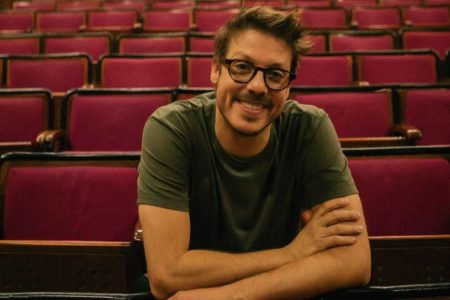 foto colorida de Fábio Porchat sorrindo debruçado em cadeiras de teatro - metrópoles