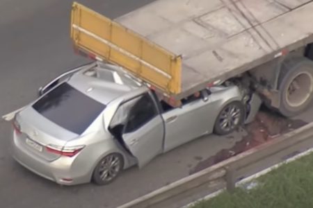 Imagem colorida de carro embaixo de caminhão após acidente - Metrópoles