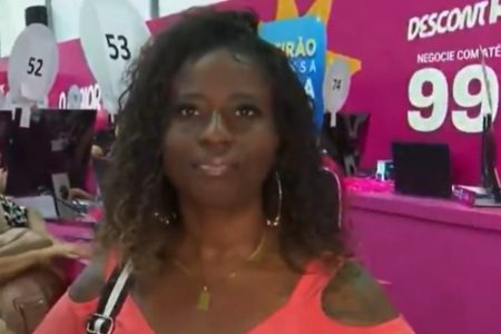 imagem de uma mulher negra, de cabelo cacheado, com camisa laranja - Metrópoles