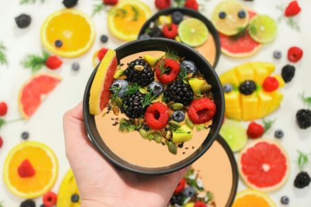Foto colorida de mão segurando bowl com frutas - Metrópoles