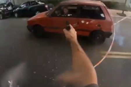 Imagem colorida de policial apontando arma a motorista em fuga. Metrópoles