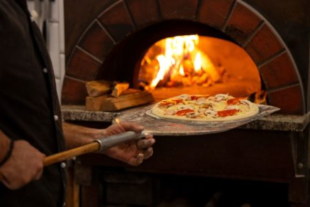 Foto colorida de uma pizza indo para o forno - Metrópoles