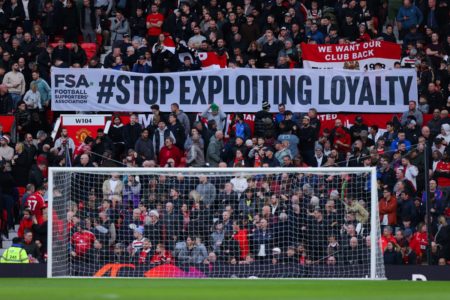 Foto colorida da torcida do Manchester United, em protesto contra alta dos ingressos no futebol inglês