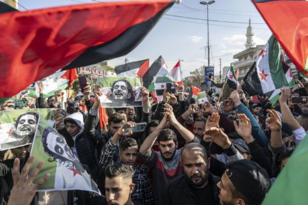 Sírios que vivem no Líbano se comemoram na rua enquanto se dirigem para a passagem de fronteira de Al-Masnaa entre o Líbano e a Síria, após o colapso de 61 anos de governo do Partido Baath na Síria