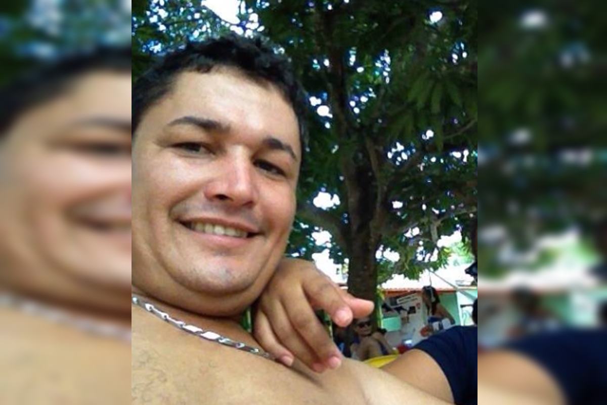 Foto colorida de homem sentado sem blusa e com cordão
