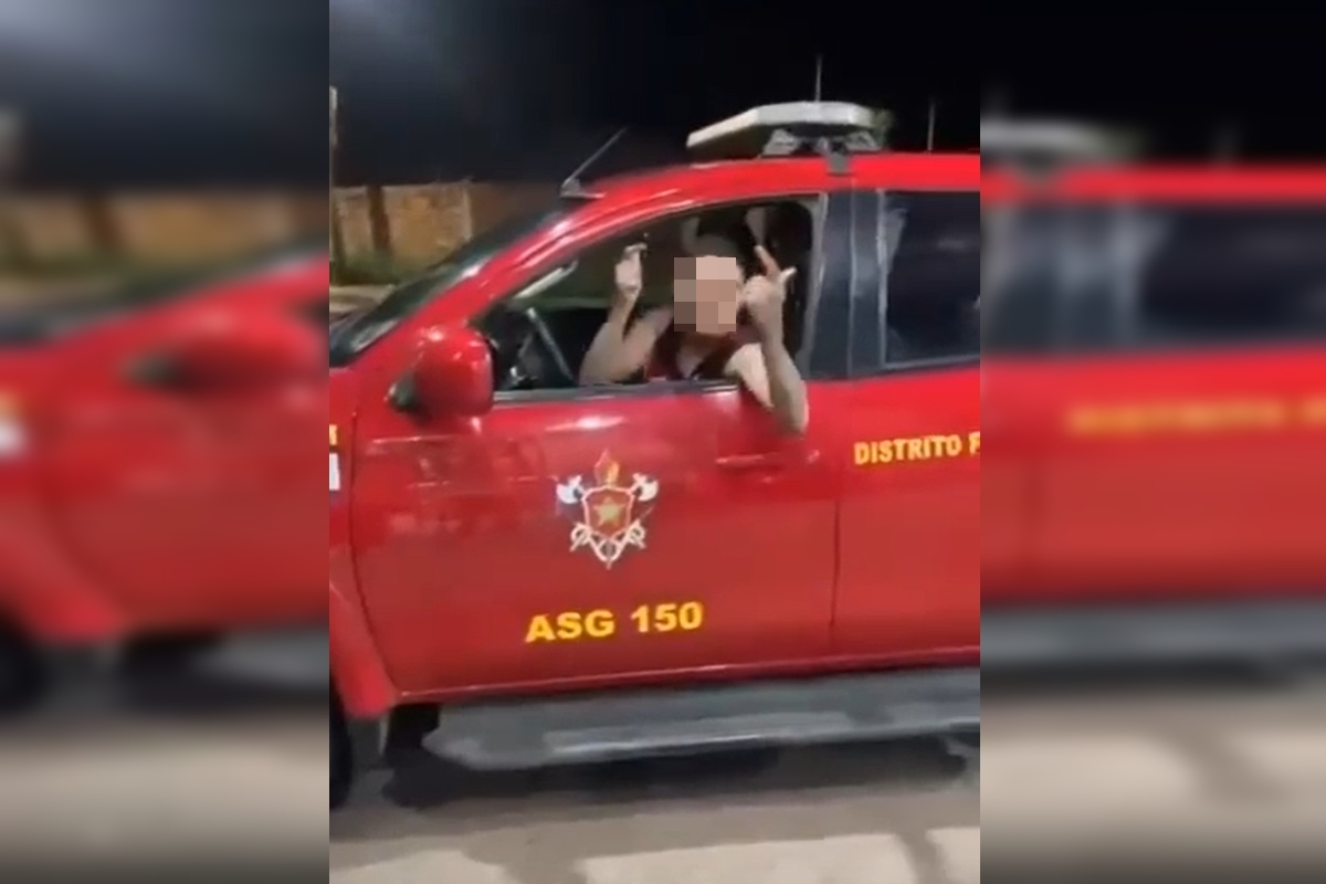 Imagem de uma viatura vermelha com letras amarelas. Um homem branco de camiseta vermelha está dirigindo. A viatura havia acabado de ser roubada