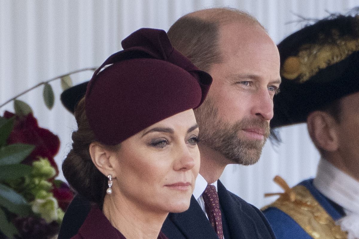 Foto colorida de mulher maquiada, com chapéu na cor vinho, ao lado de homem de barba e com terno - Metrópoles