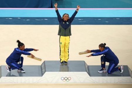Imagem colorida de Rebeca Andrade, reverenciada por Simone Biles e Jordan Chiles, no pódio das Olimpíadas de Paris- Metrópoles