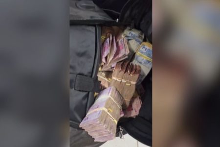 Imagem colorida mostra mochila preta com várias notas de dinheiro dentro. As notas estão agrupadas em pequenos bolos - Metrópoles