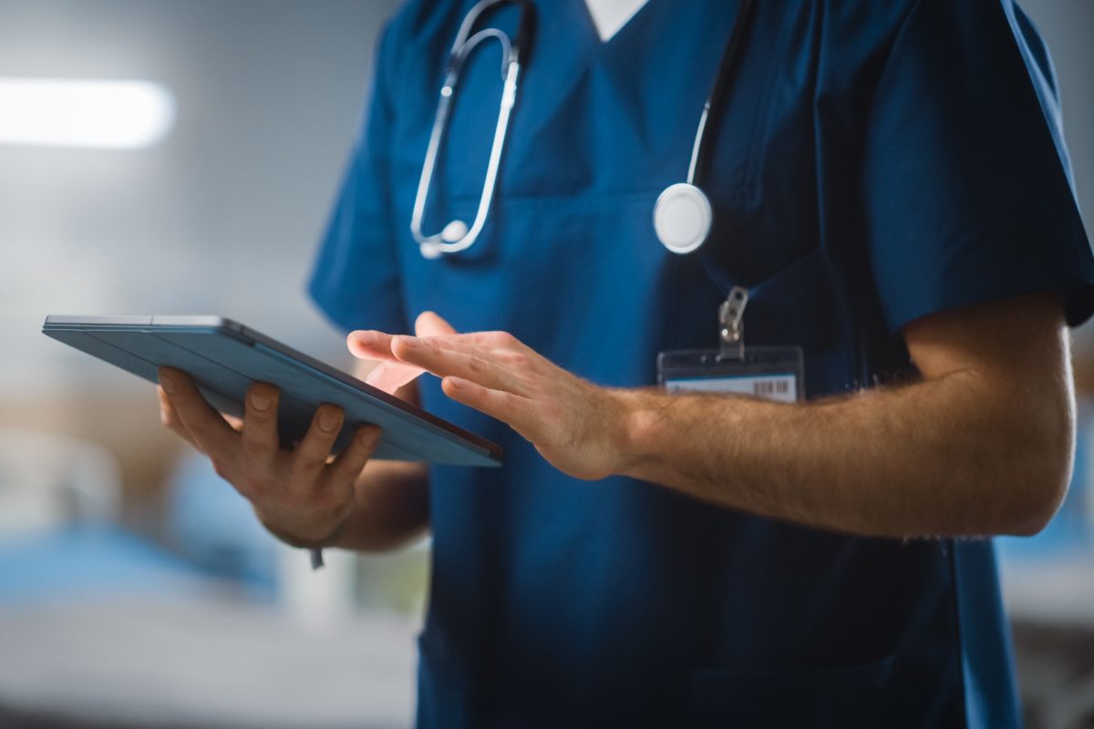 Enfermaria do hospital: Enfermeira chefe irreconhecível, médico, cirurgião usa computador tablet digital, cuidados de saúde, monitoração de sinais vitais, máquina de computador. Conceito de avanços médicos. Metrópoles