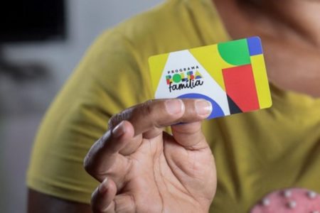 Imagem colorida de pessoa com o cartão do Bolsa Família - Metrópoles