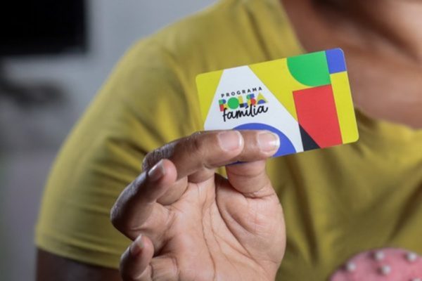 Imagem colorida de pessoa com o cartão do Bolsa Família - Metrópoles