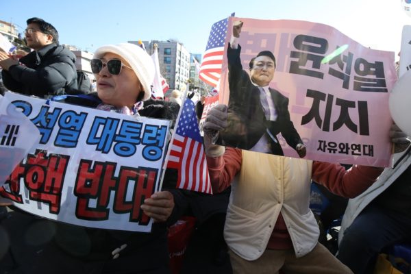 Imagem de manifestantes segurando cartazes contra o ex-presidente da coreia do sul Yoon Suk Yeol