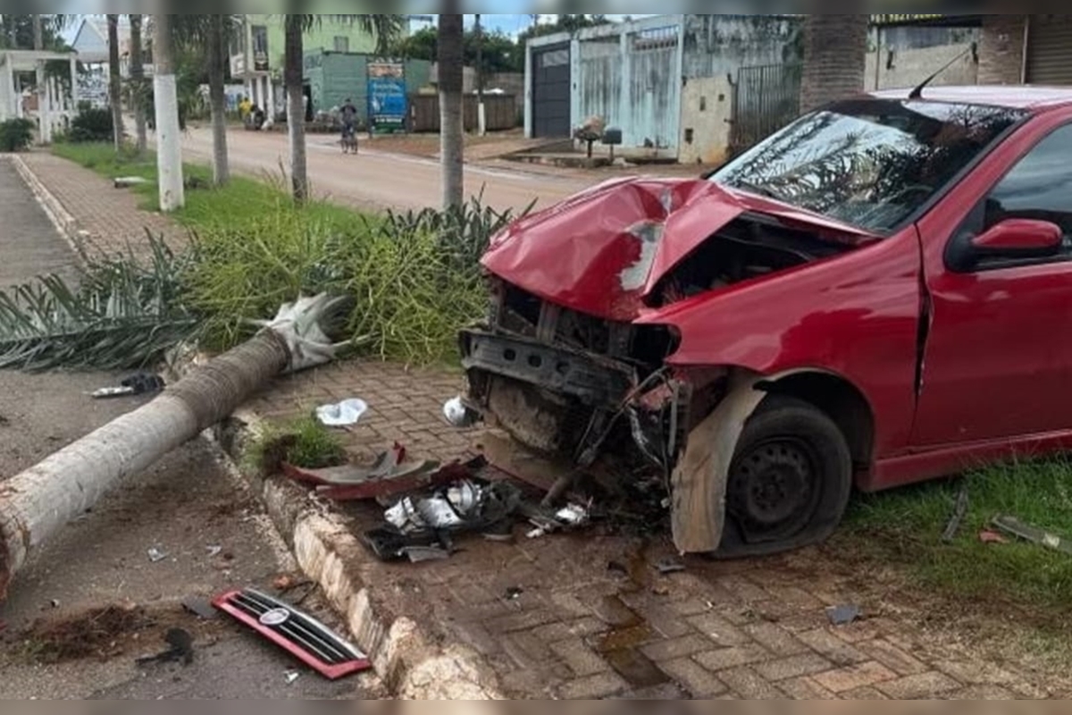Imagem de um carro vermelho colidido contra uma árvore