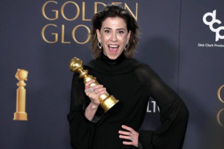 Foto colorida de Fernanda Torres sorrindo e segurando o Globo de Ouro de Melhor Atriz na mão - Metrópoles