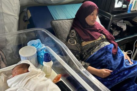 Imagem colorida, uma mulher deitada ao lado de um bebê - Metrópoles