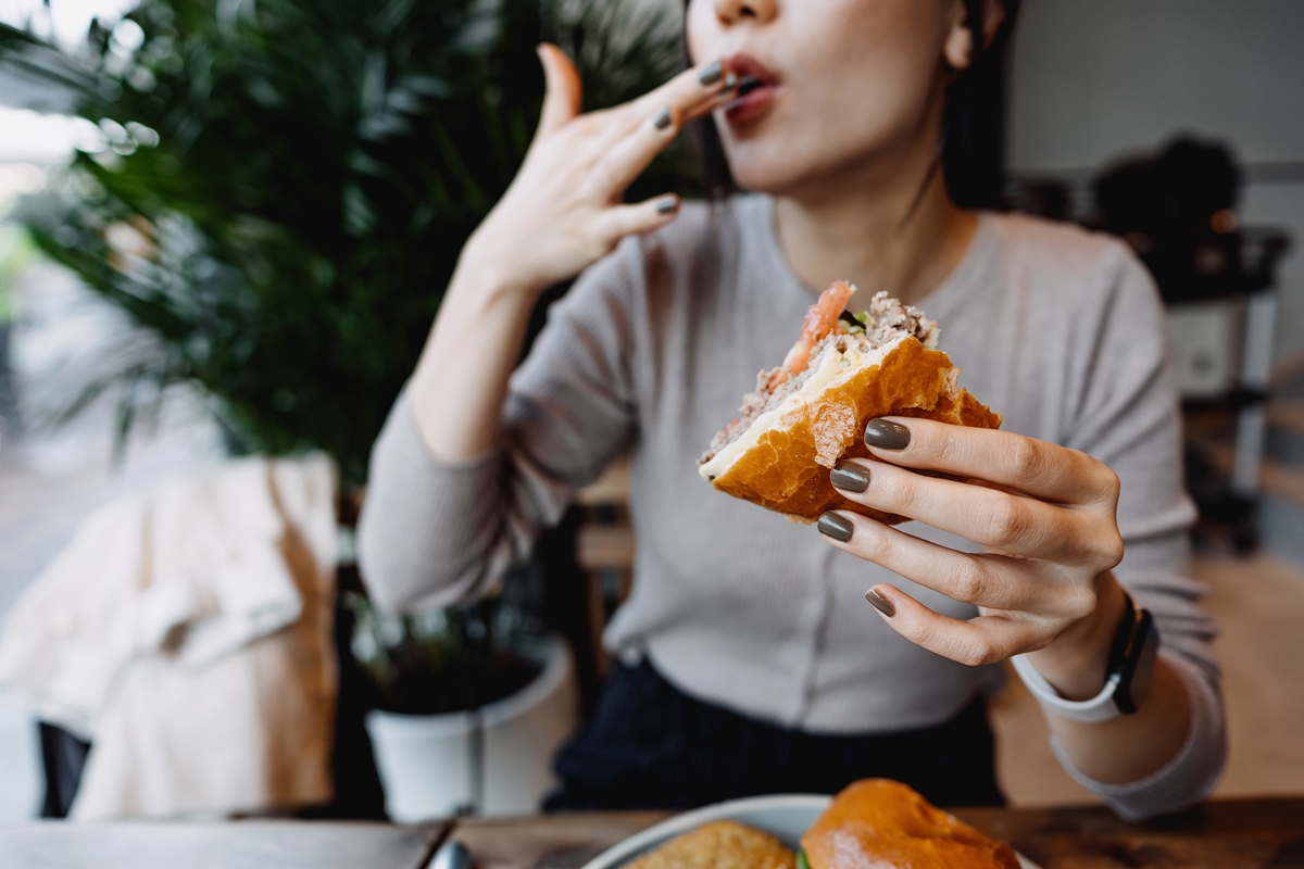 Jovem mulher asiática comendo lanche - Metrópoles