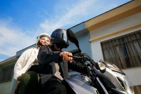Imagem colorida de duas pessoas sobre uma moto