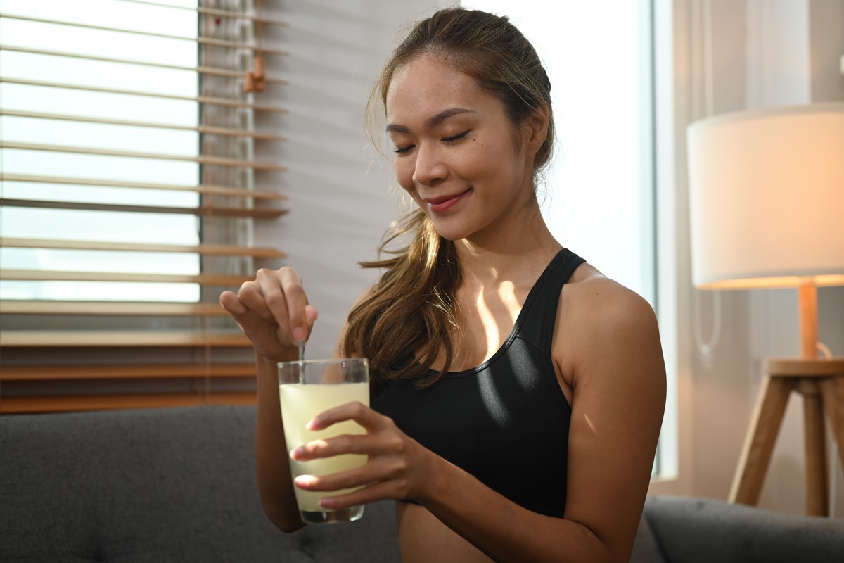 Foto colorida de mulher misturando algo dentro de um copo de suco - Metrópoles