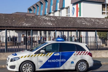 Foto colorida de carro de polícia em frente a escola, em Budapest - Metrópoles
