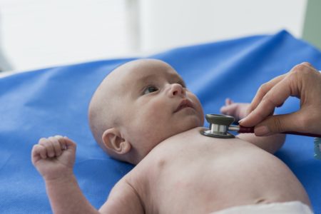 Imagem mostra um bebê careca sendo examinado com um estetoscópio - Metrópoles
