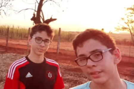 Imagem colorida de dois irmãos gêmeos vestidos com camisetas vermelha e azul - Metrópoles