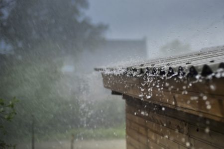Imagem colorida de telhado de casa sofrendo chuva. Metrópoles