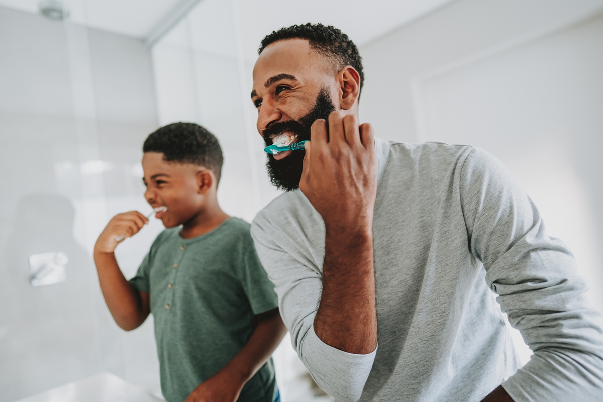 Pai ensinando filho a escovar os dentes Quando começar a escovar os dentes? Um guia da saúde bucal na infância