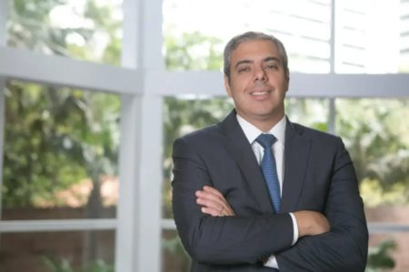 Foto posada de Milton Maluhy Filho, presidente do Itaú, vestindo terno escuro e gravata, e com os braços cruzados - Metrópoles