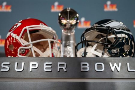 Imagem de dois capacetes de futebol americano expostos em uma bancada com os dizeres "Super Bowl" - Metrópoles