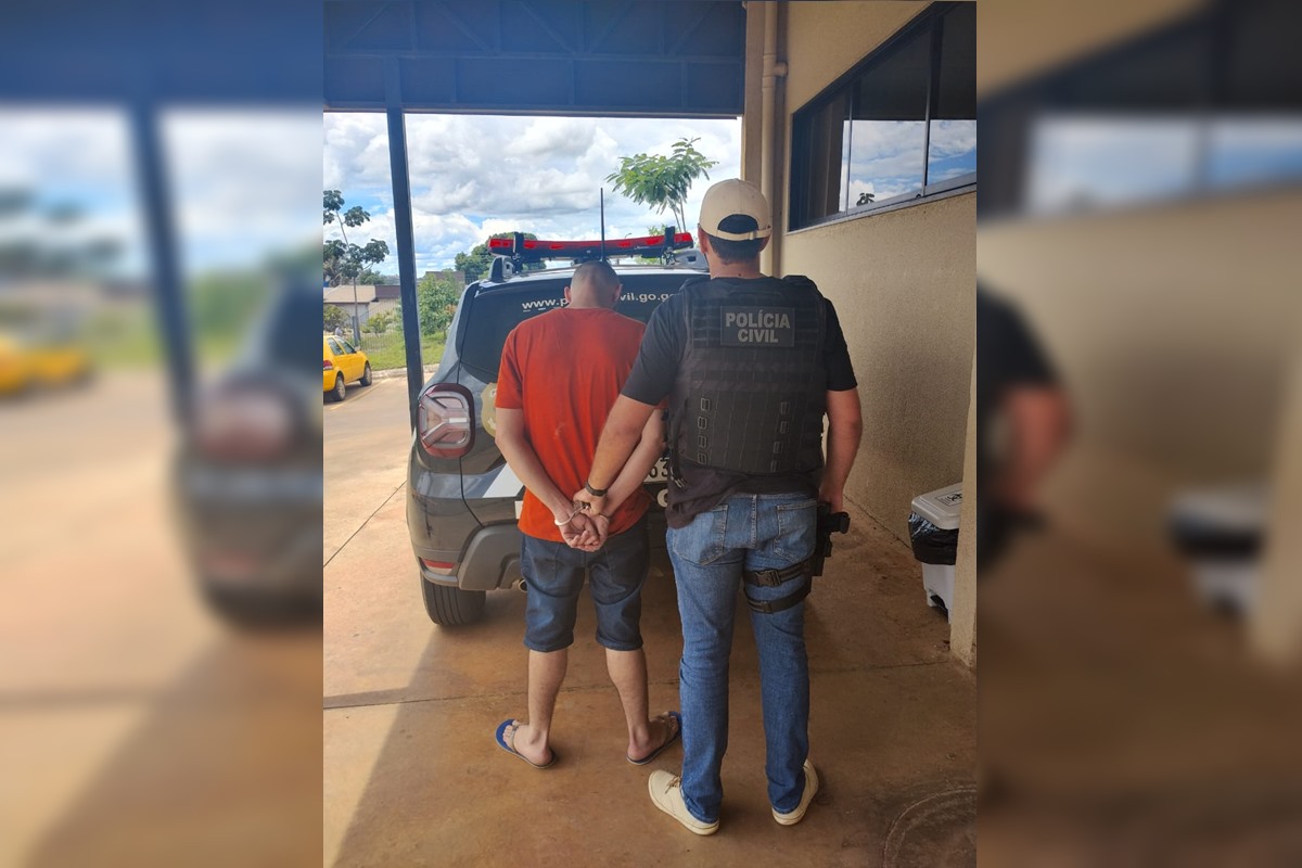 Policial conduz homem de camisa vermelha algemado