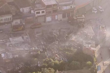Imagem aérea colorida mostra escombros de construções de madeira carbonizadas após incêndio - Metrópoles