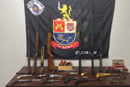 Imagem colorida de uma bancada da polícia com armas e munições apreendidas - Metrópoles