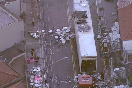 Imagem aérea colorida mostra baú de caminhão incendiado. A carga de papel higiênico está espalhada no meio da rua - Metrópoles