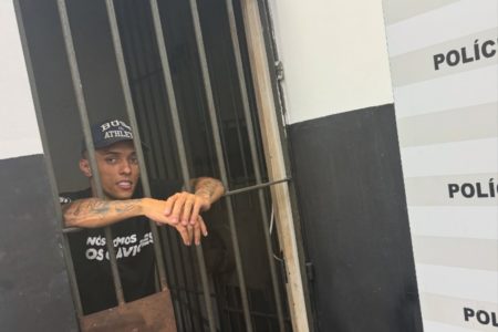 Foto colorida de influenciador Buzeira em delegacia de polícia. Ele foi alvo de um mandado de busca e apreensão. - Metrópoles