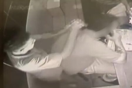 Imagem em preto e branco, de câmera de monitoramento, mostra dois homens brigando em recepção de hotel, um deles armado com uma faca - Metrópoles