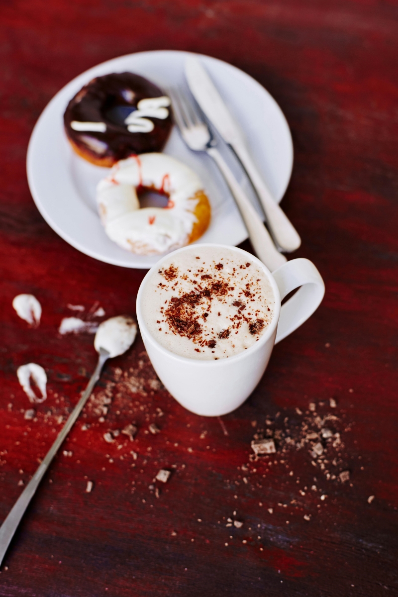 Xícara de café com doces em um prato ao lado - Metrópoles