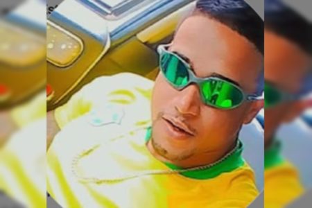 Foto colorida de homem com óculos juliete e blusa do Brasil