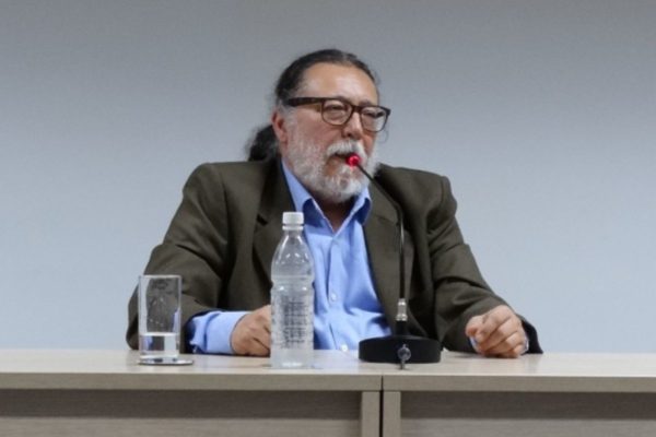 Imagem mostra um homem branco de óculos quadrados e barba branca