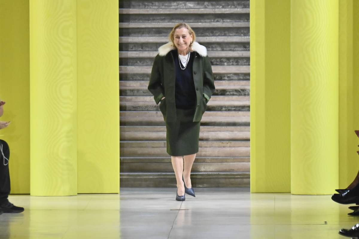 A imagem mostra a designer Miuccia Prada andando na passarela