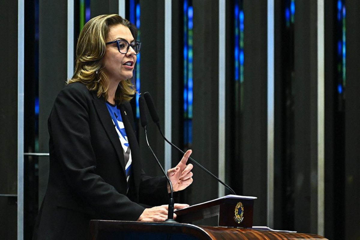 Foto colorida da senadora Leila Barros trajando um brazer preto por cima de uma blusa azul. Ela usa óculos no rosto.