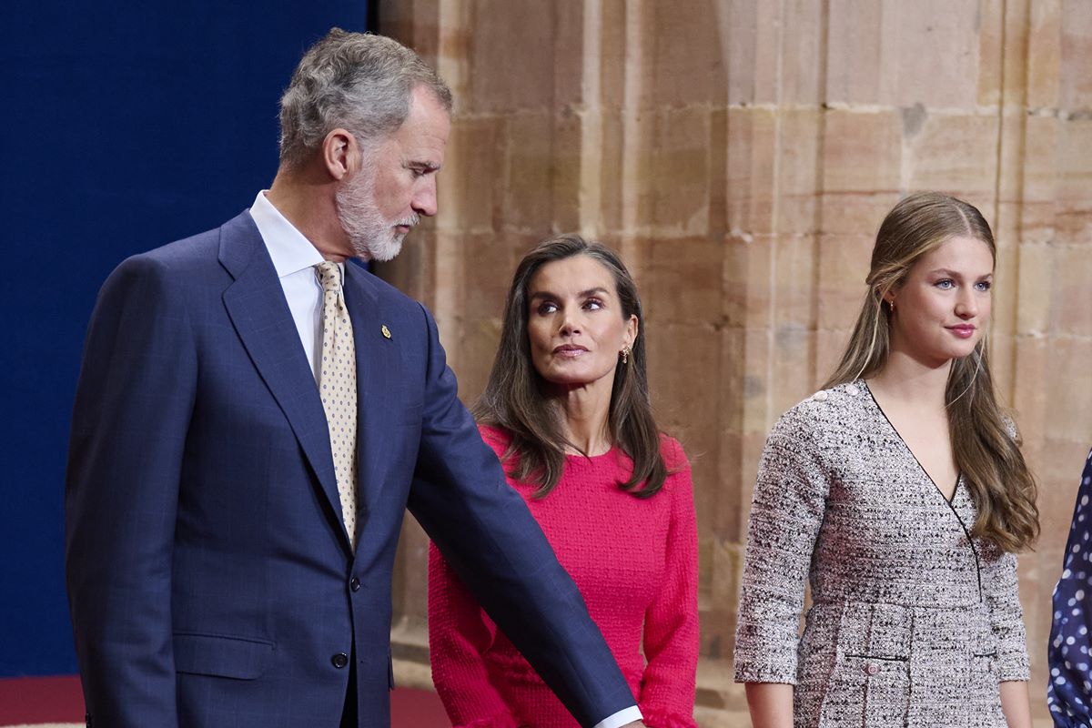 Foto colorida de homem conversando com uma mulher de vestido vermelho. Ao lado, tem outra mulher loira - Metrópoles