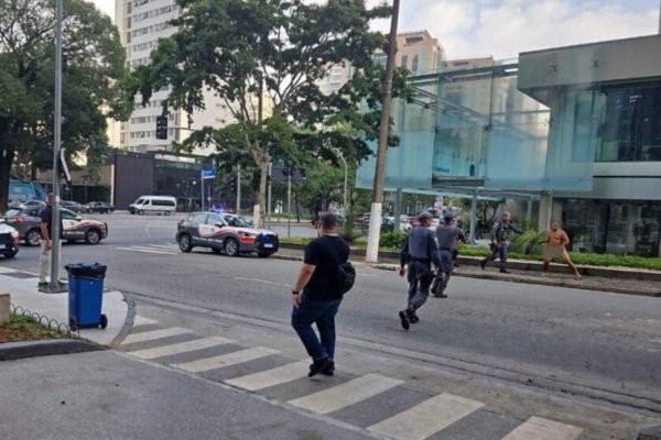 Imagem colorida de homem pelado sendo abordado por policiais militares. Metrópoles