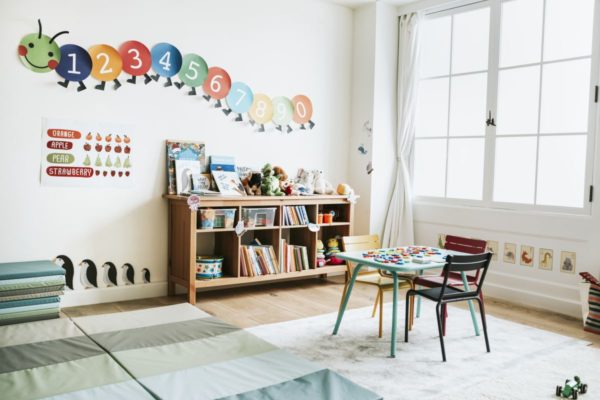 Imagem colorida de uma creche com detalhes coloridos, livros e uma mesa - Metrópoles