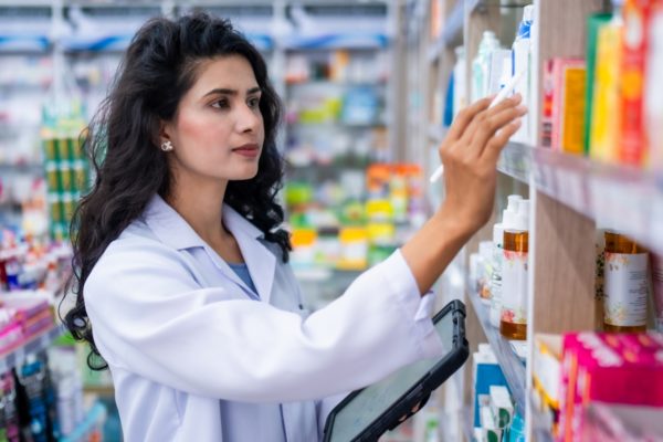 Jovem mulher farmacêutica analisando produtos em farmácia - Metrópoles