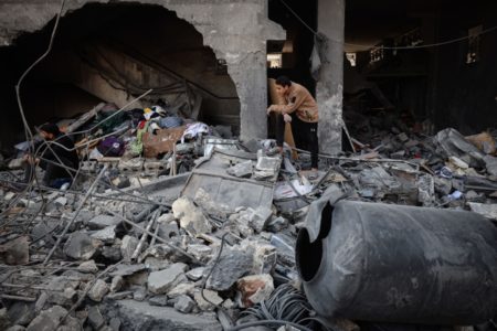 Pessoas vasculham os destroços de uma casa após um ataque israelense na Cidade de Gaza em 18 de março de 2025.