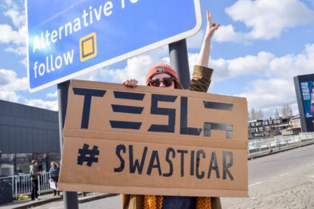 Imagem de manifestante protestando contra a Tesla, empresa de Elon Musk, com um cartaz - Metrópoles
