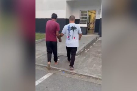 Imagem colorida mostra homem sendo conduzido a delegacia após ser preso por estuprar o enteado de 5 anos - Metrópoles